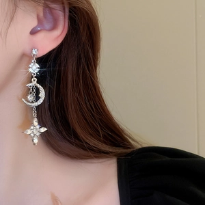 Close-up of model wearing silver star and moon tassel earrings with sparkling crystals