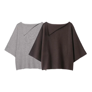 Close-up of knit texture on loose poncho style sweater and midi skirt set in neutral tones
