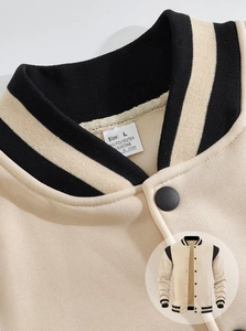 Detail of striped rib knit collar and snap button on a beige American style varsity jacket