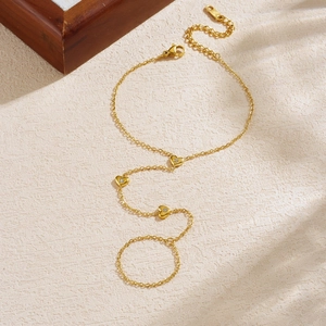 Gold stainless steel hand chain ring with sparkling heart charms on a stone background