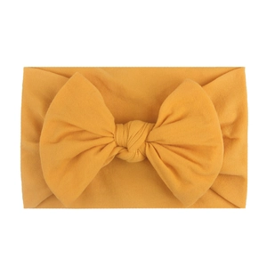 Soft mustard yellow nylon infant headband featuring a large knitted bow for baby girls