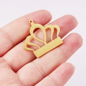 Polished gold crown shaped stainless steel pendant held in hand for jewelry DIY