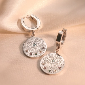 Silver evil eye hoop earrings with colorful gems on beige silk fabric