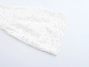 Détail de la manche en dentelle blanche avec motifs ajourés élégants et texture délicate