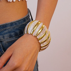 Detail of wide stretch bracelet featuring gold metal and marbled white acrylic components