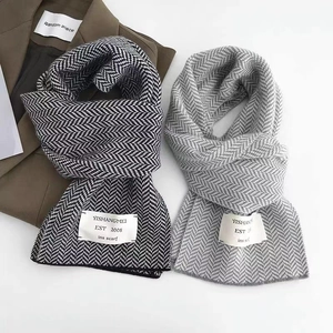 Détail d'écharpes en tricot à chevrons noirs et gris avec étiquettes blanches de marque