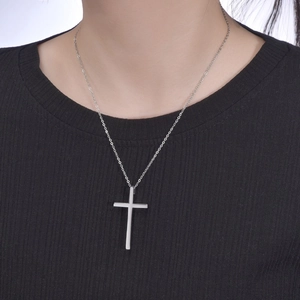 Detailed close-up of a silver cross pendant on a sleek metal chain for men