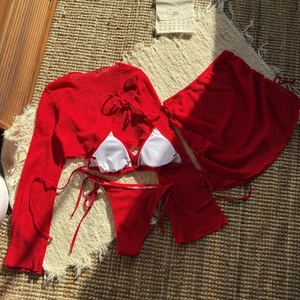 Dettaglio flat lay di un bikini rosso a quattro pezzi con copricostume e gonna mesh