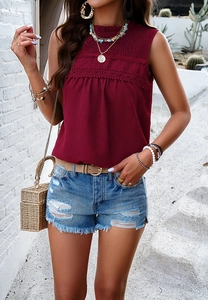 Detail view of red sleeveless top with lace trim paired with distressed denim shorts