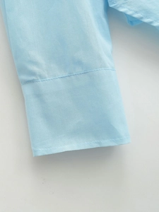 Detailed close-up of light blue shirt cuff showing premium fabric texture and stitching