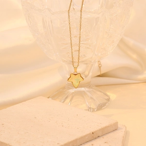 Détail d'un collier feuille d'érable doré avec pierre œil de chat sur un verre
