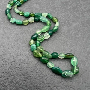 Close-up of natural irregular green agate stones and polished gemstone beads necklace