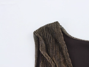 Detailed view of the gold metallic pleated shoulder strap on a black party dress