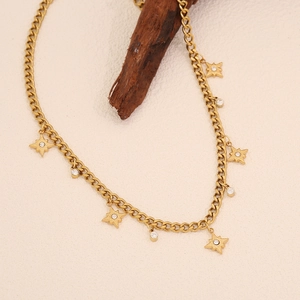 Détail d'un collier chaîne cubaine dorée avec pendentifs étoile et cercle sur bois