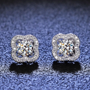 Macro shot of silver four-leaf clover moissanite earrings with halo set small diamonds