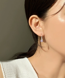 Detail of a 925 sterling silver earring with a lavender bead pendant on a model's ear