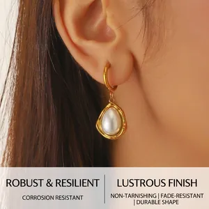 Close-up of a gold-plated drop earring with a large water drop pearl on a model's ear