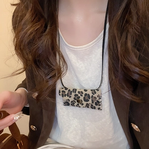 Macro detail of leopard print leather mini pendant bag with metal button and black strap
