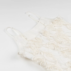Detail of 3D rose appliqué and delicate spaghetti straps on a white elegant dress