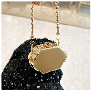 Detail of a golden octagonal mini evening bag with a pearl-style chain handle