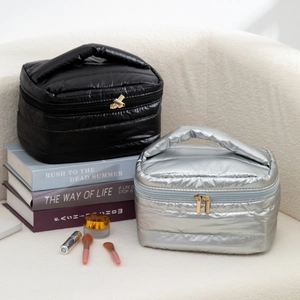 Detail of quilted puffer makeup bags with dual zippers and handles in silver and black