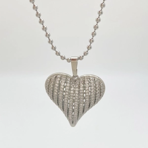 Macro shot of silver heart pendant with vertical striped cubic zirconia on ball chain