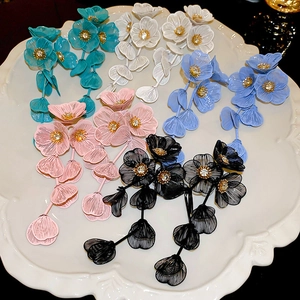 Detailed macro view of multi-colored floral tassel earrings with mesh petals on white tray