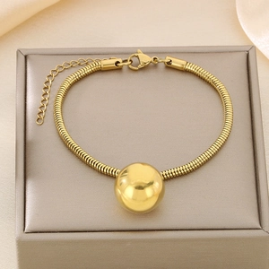 Detailed macro of 18K gold plated hollow ball pendant on a square snake chain bracelet