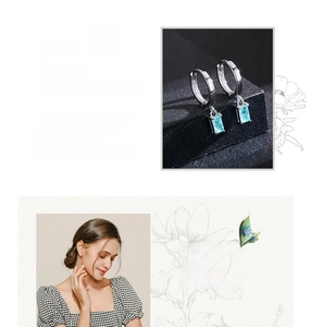Detail of silver S925 huggie earrings with a rectangular blue gemstone on model