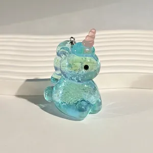 Macro detail of a light blue translucent acrylic unicorn pendant with glitter and a pink horn