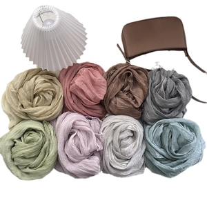 Collection of pleated vintage silk scarves in various pastel colors on a white background
