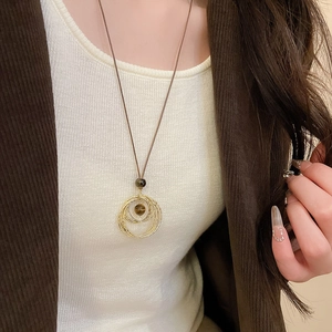 Detail of tiger eye stone pendant necklace layered with gold rings on cord chain