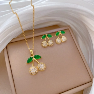 Detailed view of cherry jewelry set with green leaf and white zircon on silk