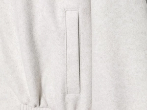 Detail of wool bomber jacket side pocket showing fine stitching on soft cream fabric