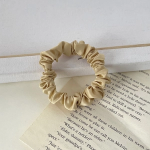 Detailed view of a champagne gold satin hair scrunchie with fine pleats on vintage paper