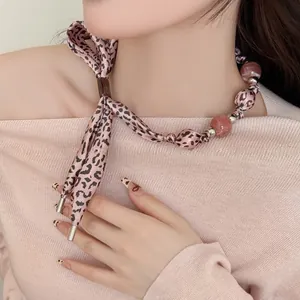 Close-up of pink leopard print ribbon necklace with marble beads on model neckline