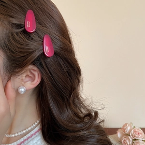 Gros plan de barrettes en acrylique magenta élégantes portées avec des perles