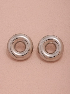 Macro detail of polished silver hoop earrings showing smooth hollow donut shape texture