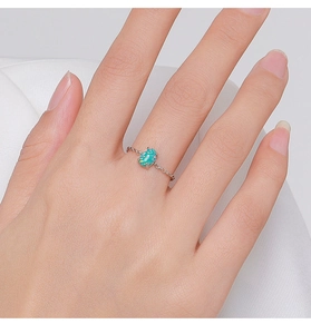 Close-up of 925 sterling silver ring featuring a small oval blue opal on a model's finger
