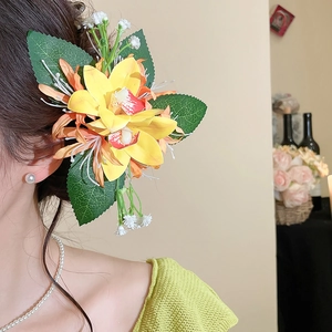 Detail of yellow fabric orchid hair clip with green leaves on model's side profile