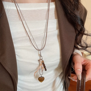 Detail of vintage double-layer necklace with coral charms and tiger eye heart pendant