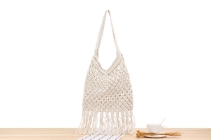 Detail of handmade macramé beach bag featuring geometric hollow mesh and long tassels