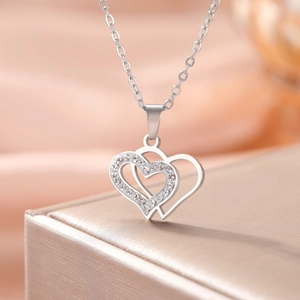 Macro detail of silver interlocking heart necklace with crystals on champagne satin