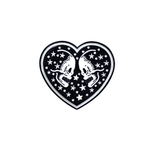 Detailed close-up of gothic heart enamel pin with black and white skull and star design