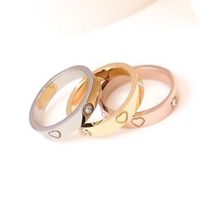 Close-up of titanium steel rings in silver, gold and rose gold with heart engravings
