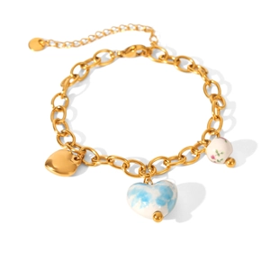 Bracelet à chaîne dorée avec breloques en cœur céramique et perles à fleurs sur blanc