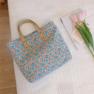 Detailed shot of floral canvas tote bag with leather handles and gold rivet accents