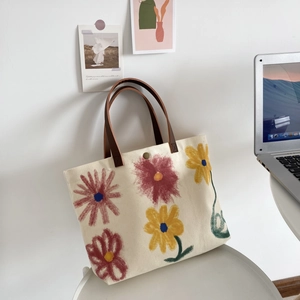 Cream canvas tote bag with colorful hand-painted floral prints and brown handles