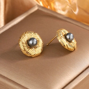 Macro detail of retro 18K gold plated earrings featuring spiral texture and grey pearl