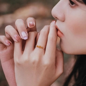 Close-up of rose gold ring with yellow gemstones and pink stones on model's hand